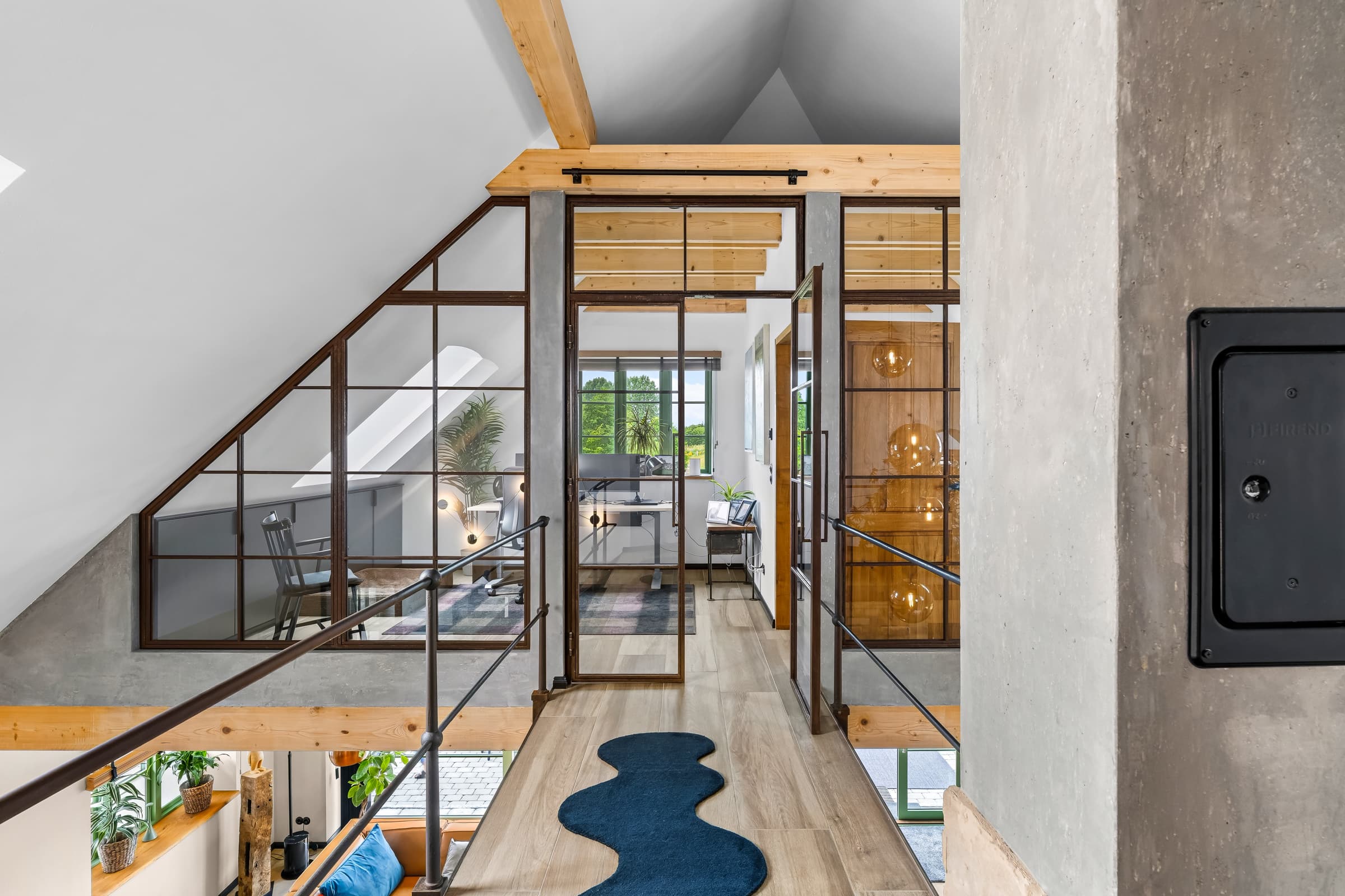 Blick durch die Stahl-Glas-Wand über die Galerie in das Arbeitszimmer unter der Dachschräge