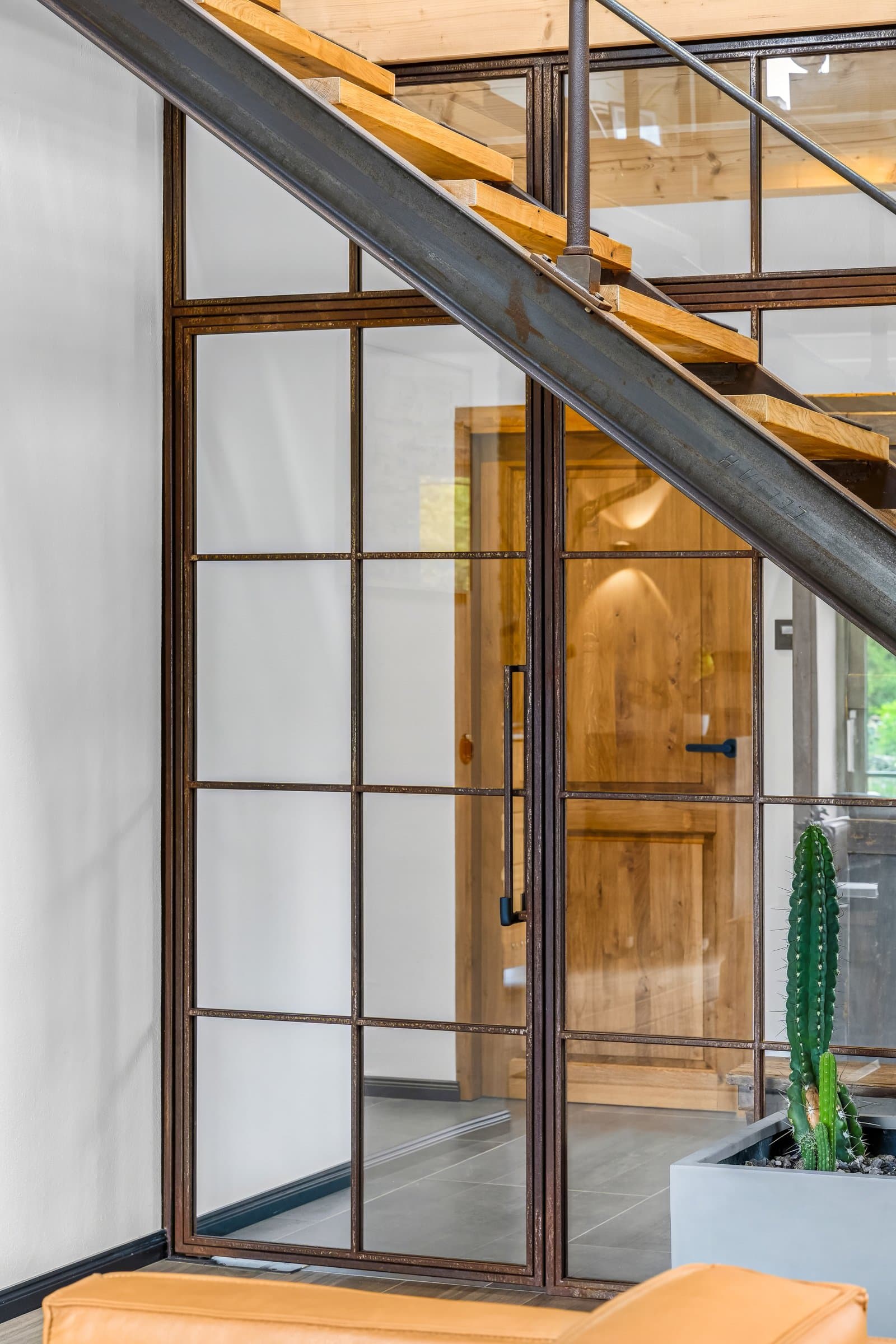 Glastür mit Rohstahl-Rahmen in der Nische unter der Stahltreppe