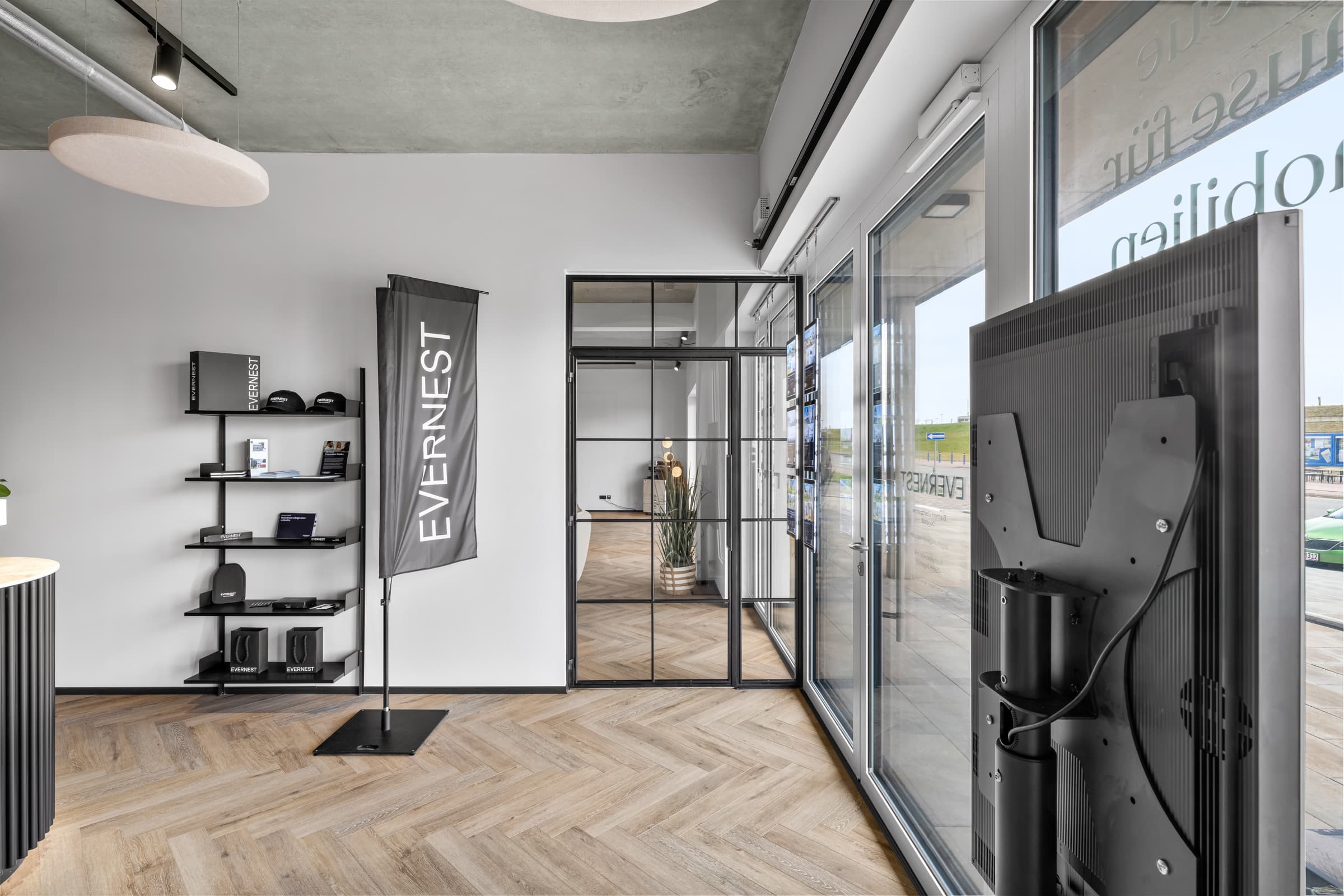 Arbeitsbereich hinter raumhoher Stahl-Glas-Front mit Fischgrätparkett im Immobilienbüro