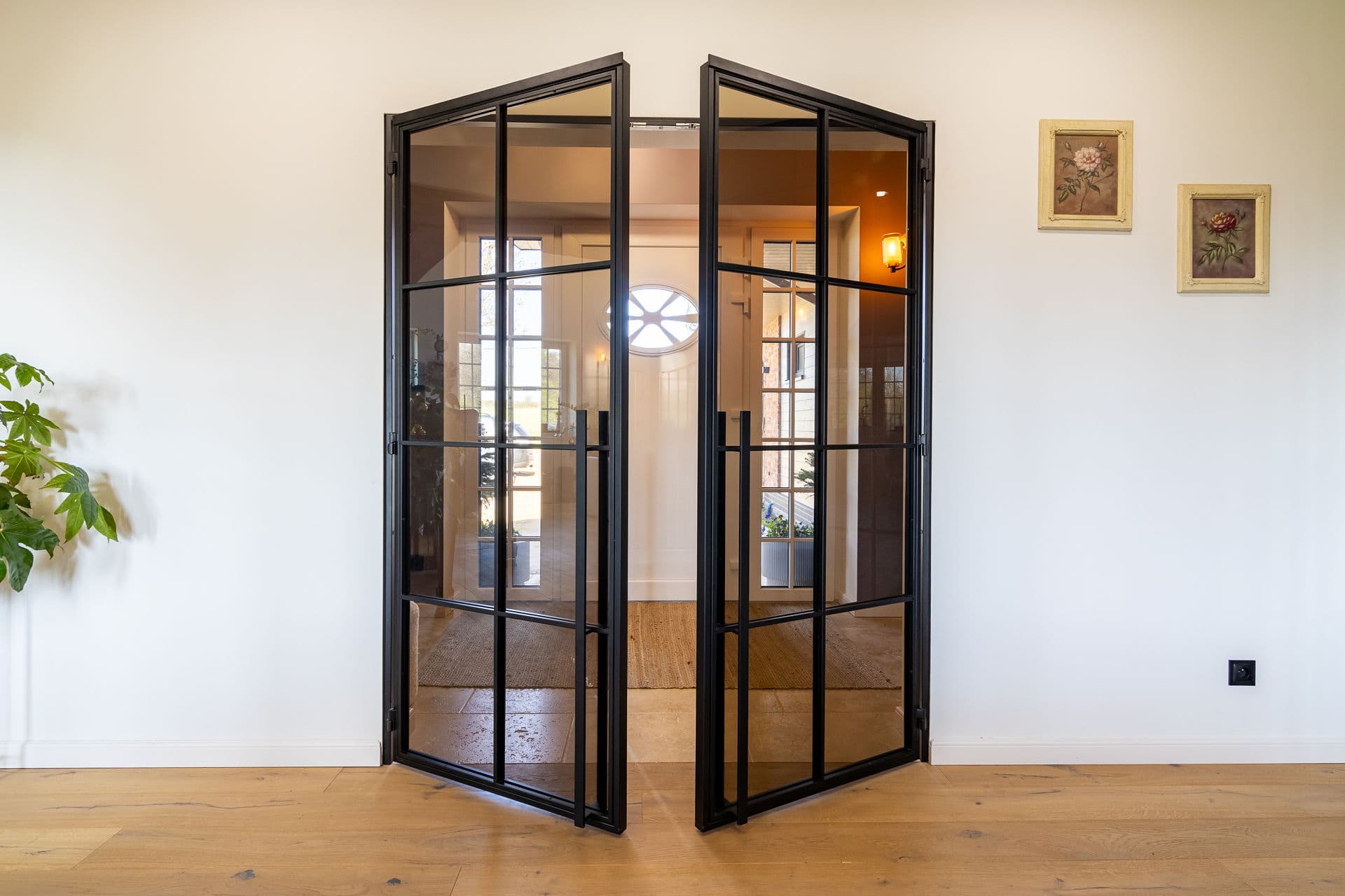 Doppeldrehtür aus Stahl und Glas mit Blick auf den Flur mit Rundbogenfenster