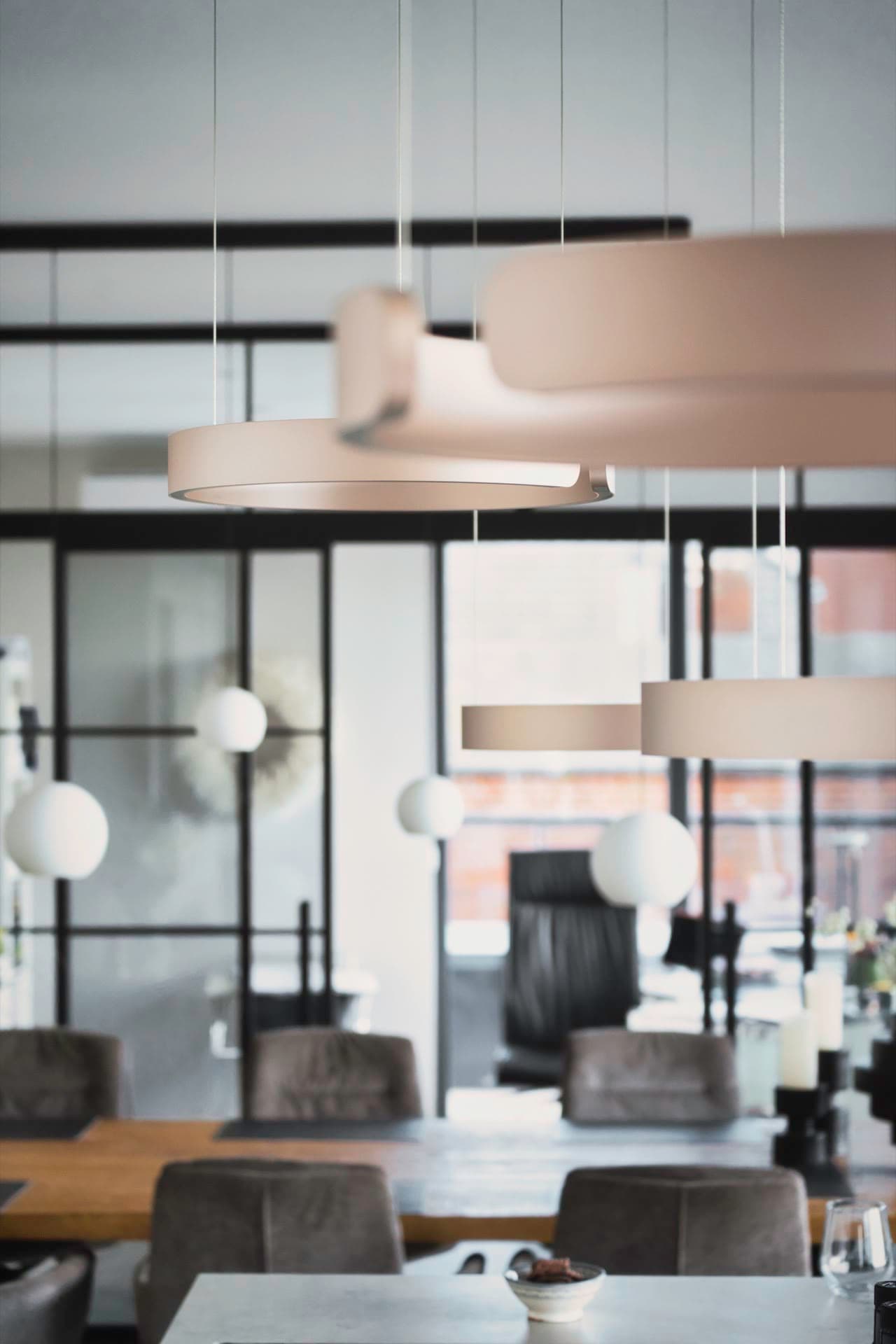 Wohnbereich mit Designerleuchten und Doppelschiebetür aus Stahl und Glas im Hintergrund