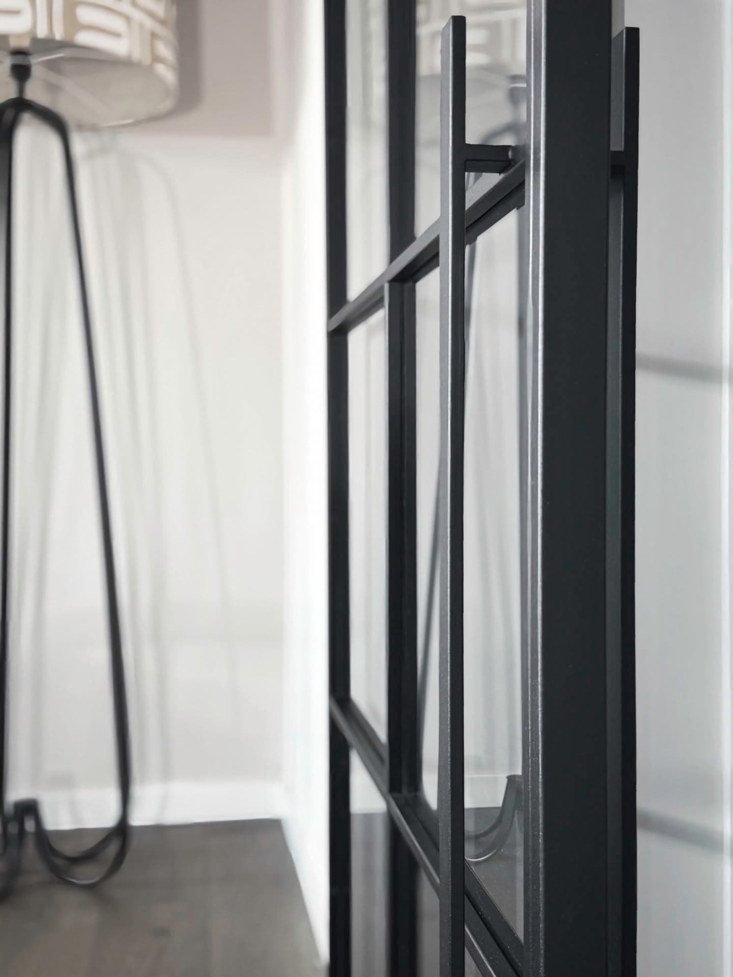 Nahaufnahme des Stahl-Glas-Rahmens der Doppelschiebetür mit Blick auf eine Stehlampe