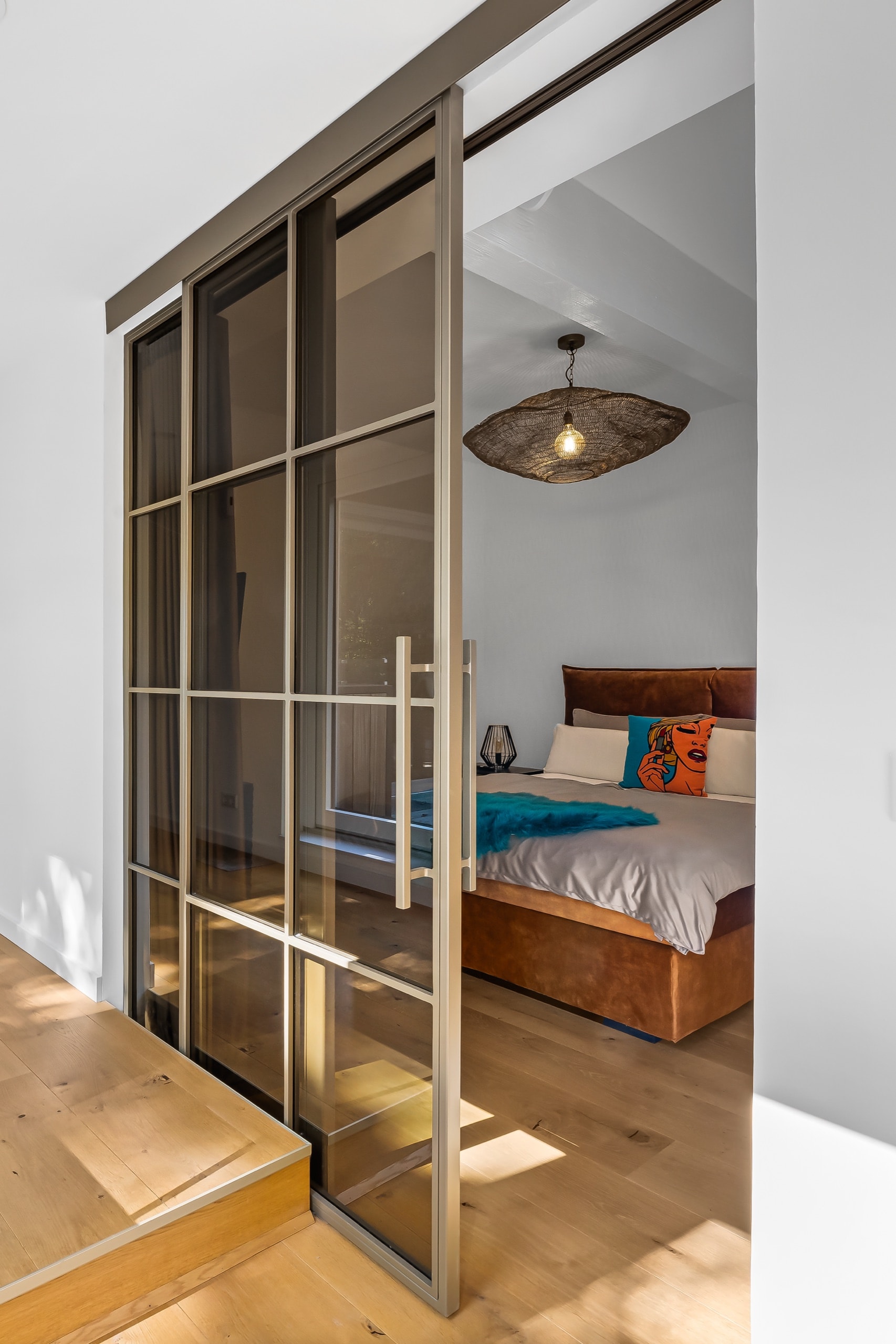 Schiebetür zum Schlafzimmer mit Blick auf das Bett und eine Pendelleuchte