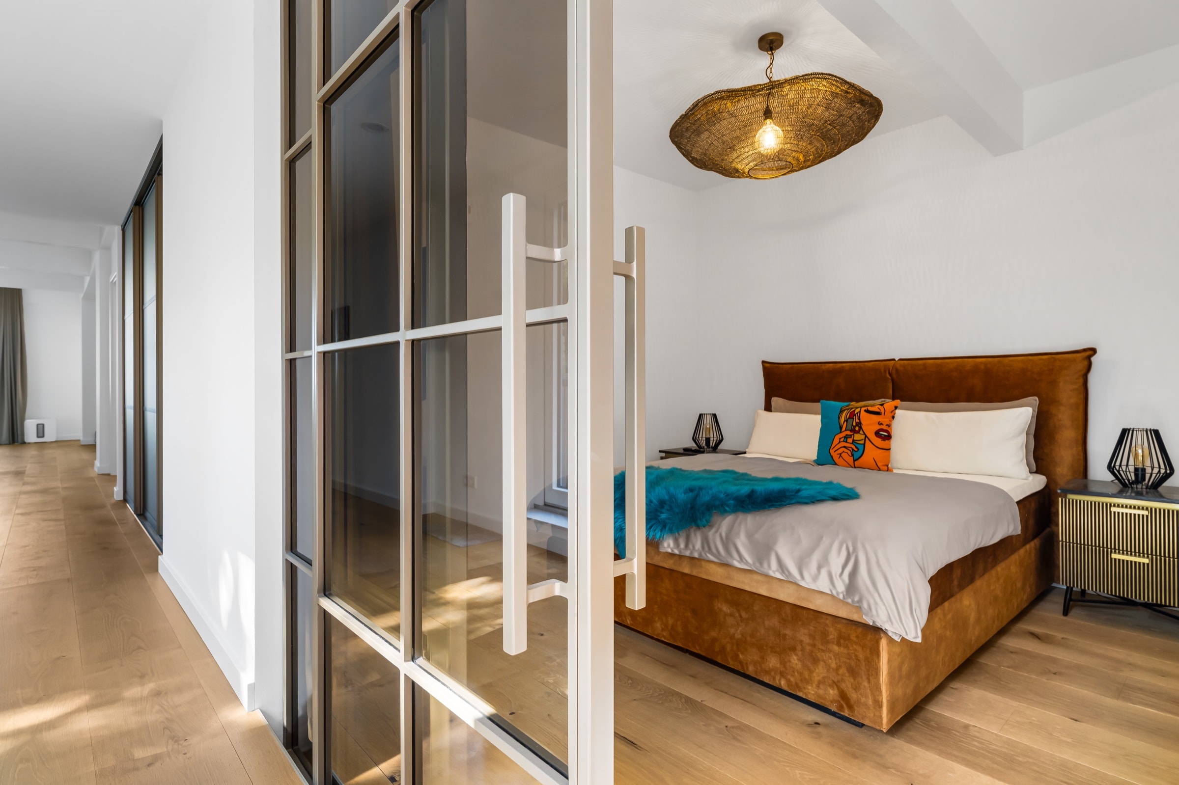 Stangengriff der geöffneten Schiebetür am Schlafzimmer, dahinter Bett mit Lederkopfteil und geflochtene Pendelleuchte