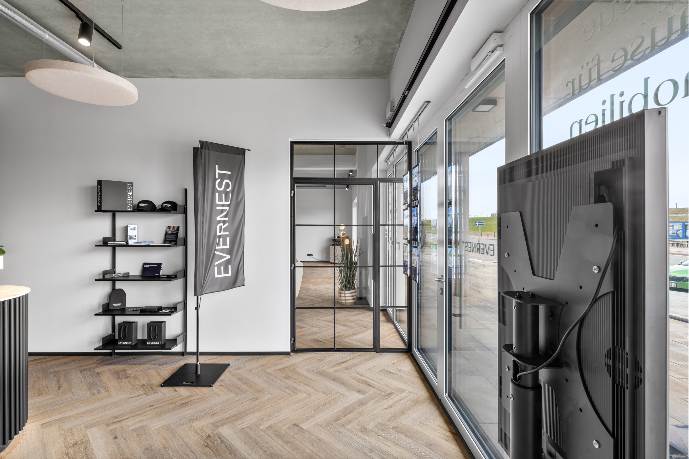 Arbeitsbereich hinter raumhoher Stahl-Glas-Front mit Fischgrätparkett im Immobilienbüro