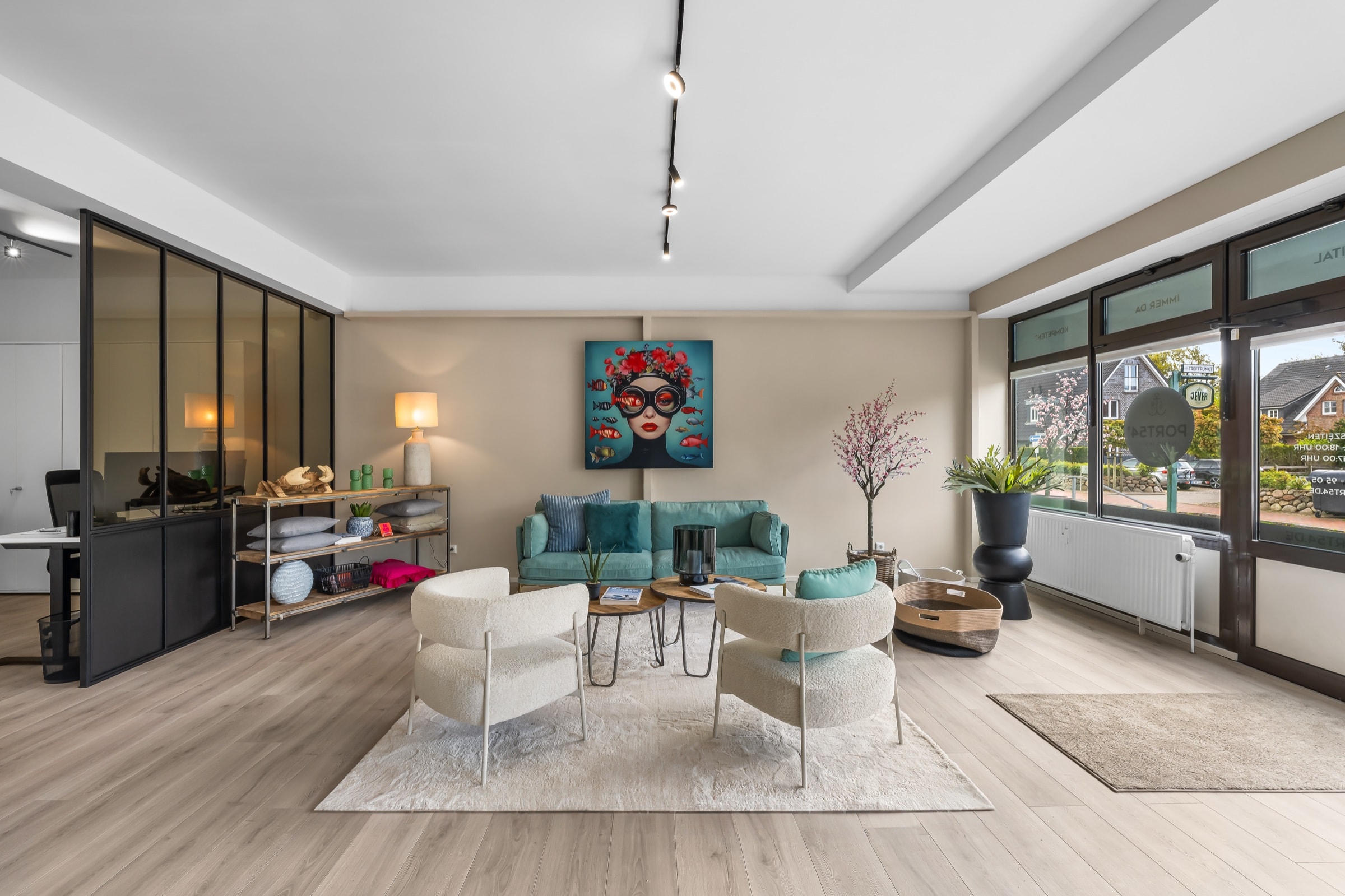Empfangs-Lounge mit türkisem Sofa, hellem Holzboden und raumhoher Trennwand aus Stahl und bronziertem Glas