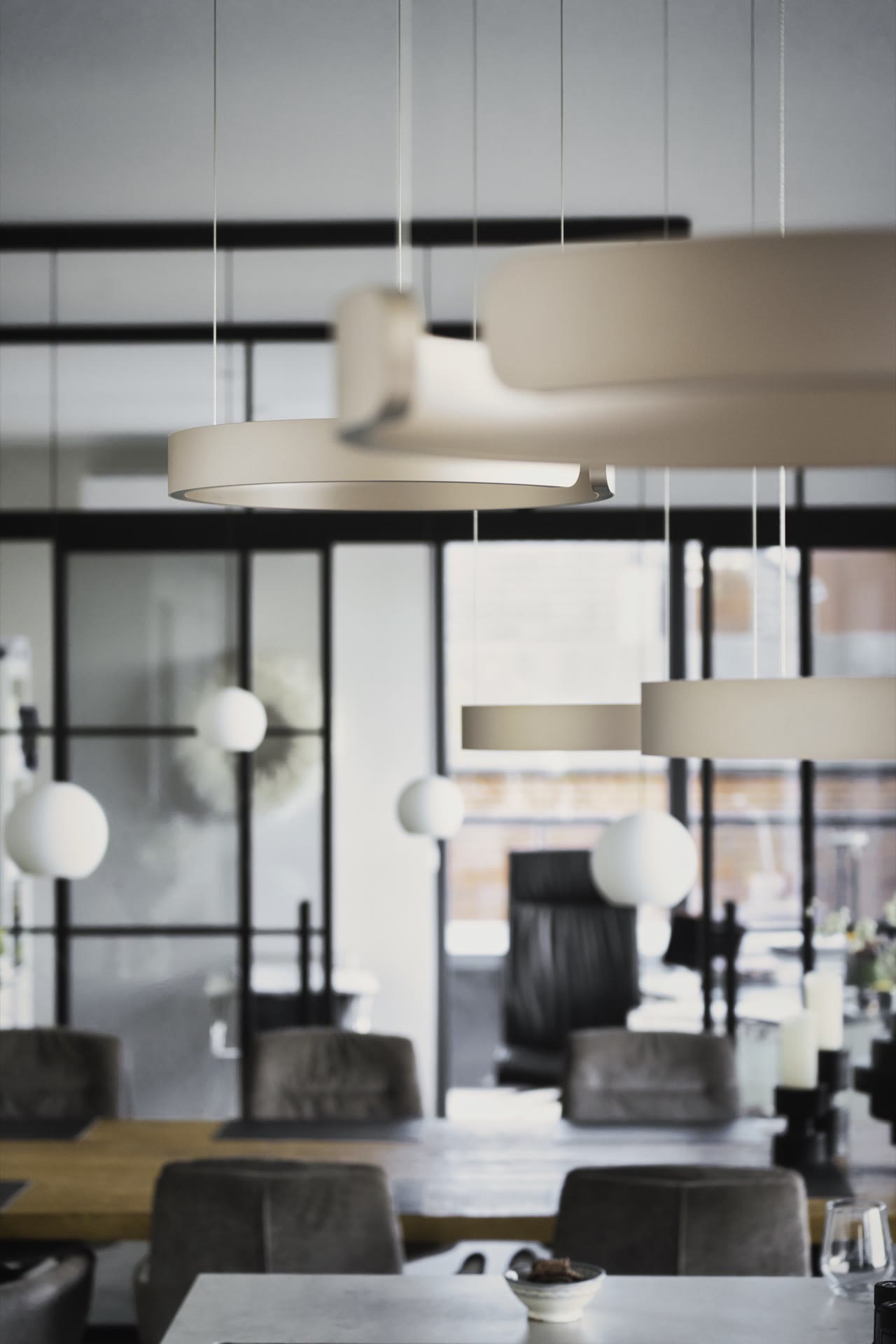 Wohnbereich mit Designerleuchten und Doppelschiebetür aus Stahl und Glas im Hintergrund