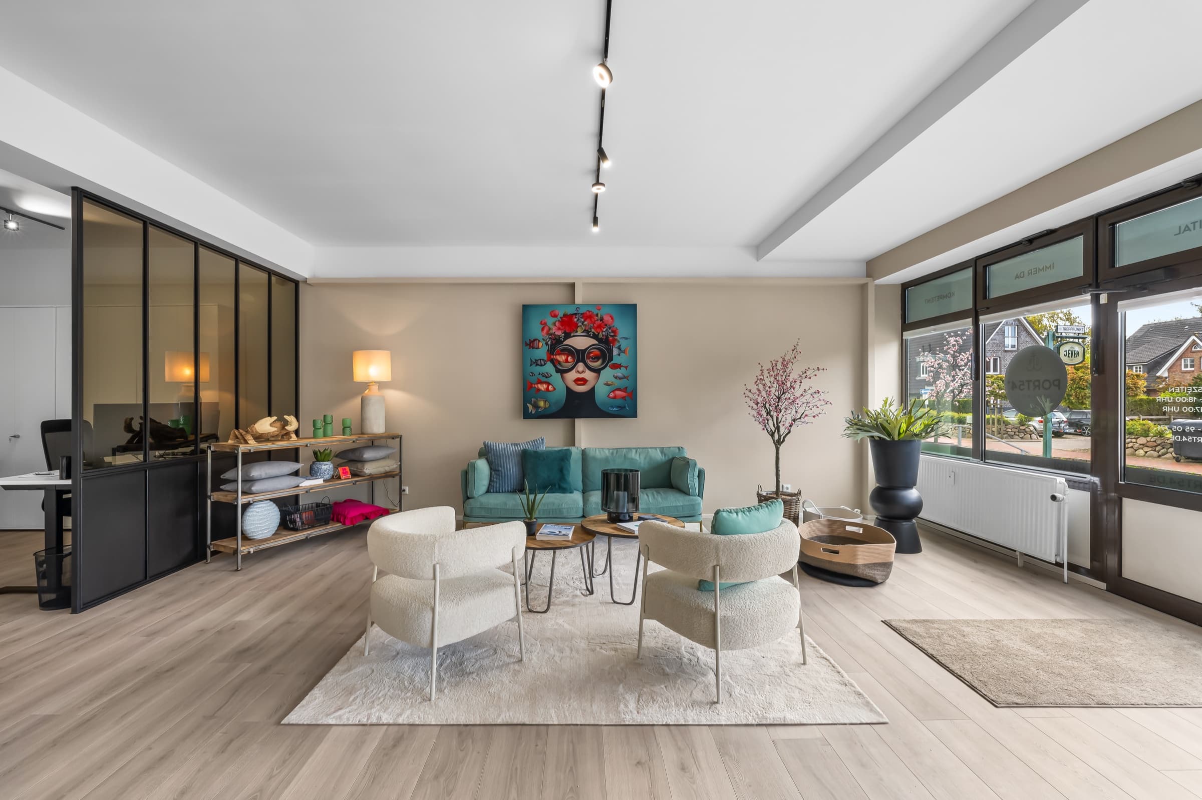 Empfangs-Lounge mit türkisem Sofa, hellem Holzboden und raumhoher Trennwand aus Stahl und bronziertem Glas