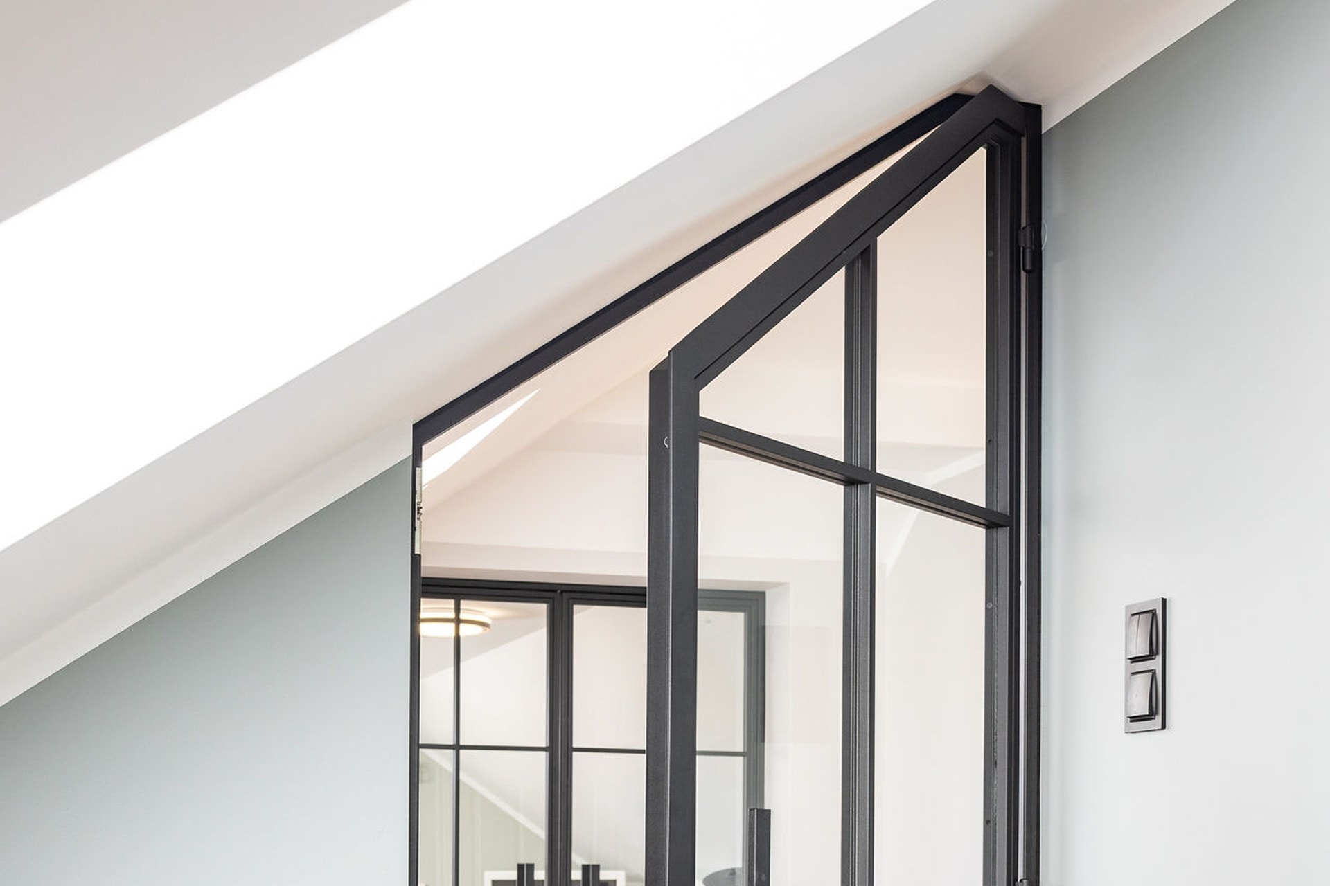 Stahl-Glas-Tür mit schräg zugeschnittener Oberkante, exakt an die Dachschräge im Landhaus angepasst