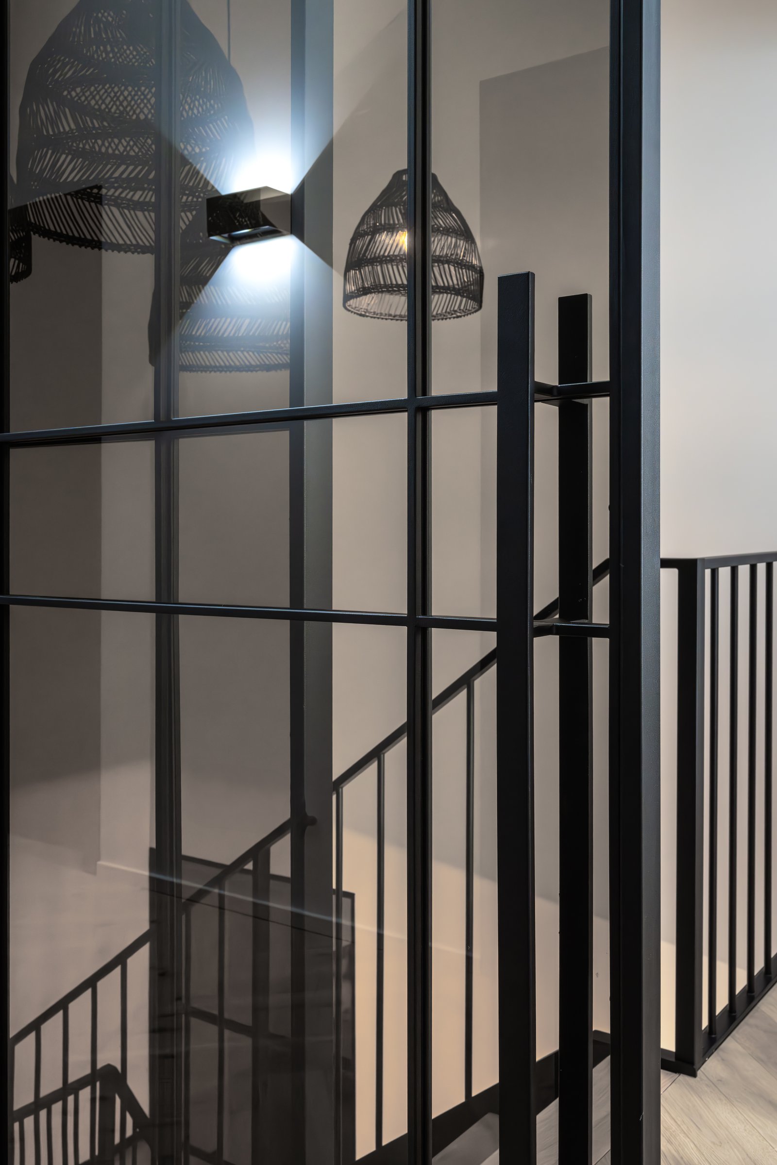 Bronziertes Glas vor schwarzen Geländerstäben der Treppe, zwei Ebenen in einem Bildausschnitt