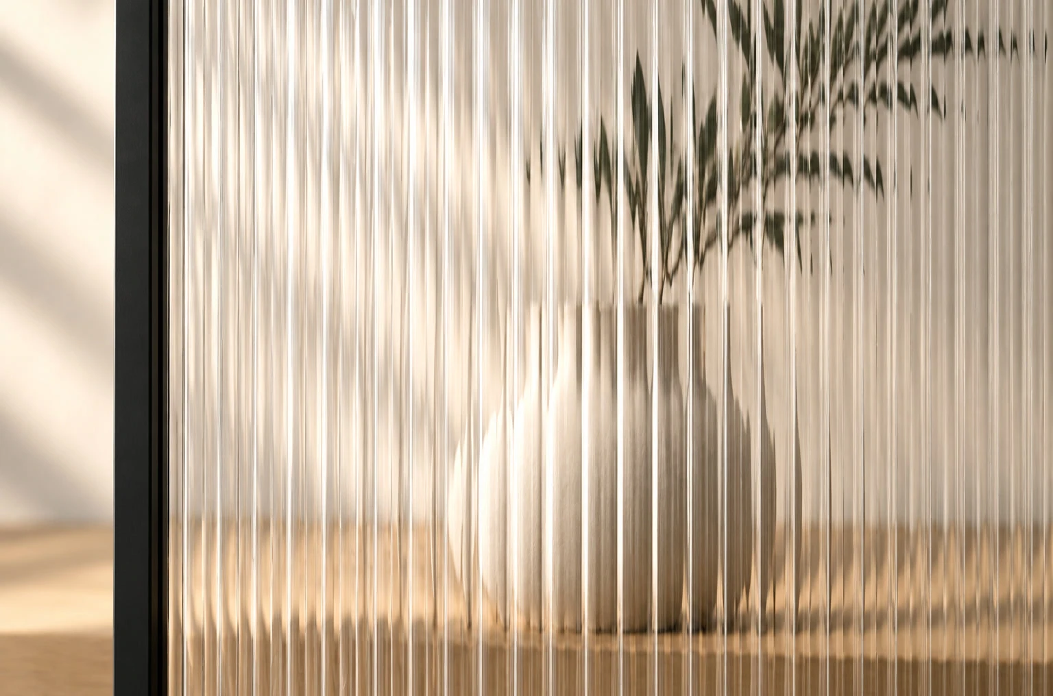 Riffelglas an einem schwarzen Stahlprofil, dahinter Vase und Zweig im Licht